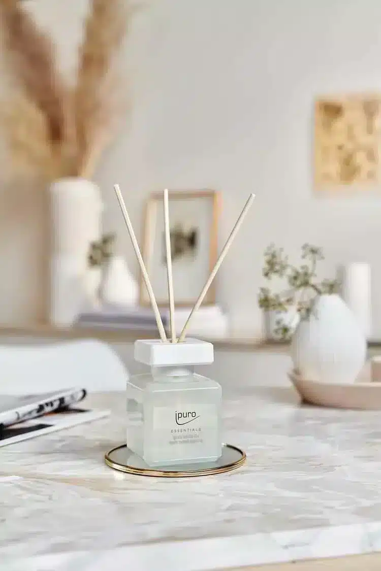 Ipuro Essentials White Lily geurstokjes in wit flesje op marmeren tafel met vazen op de achtergrond