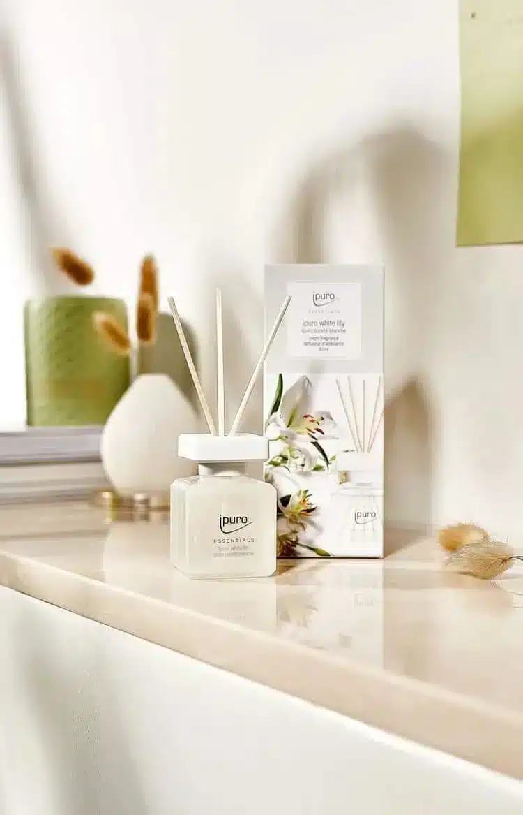 Ipuro Essentials White Lily geurstokjes naast verpakking met lelieprint op een lichte plank