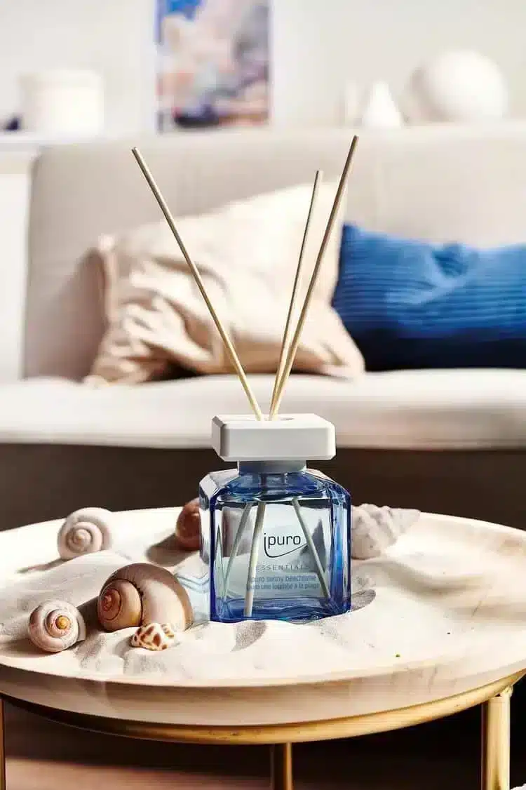Ipuro Essentials Sunny Beachtime geurstokjes in blauwe fles met schelpen op een ronde tafel