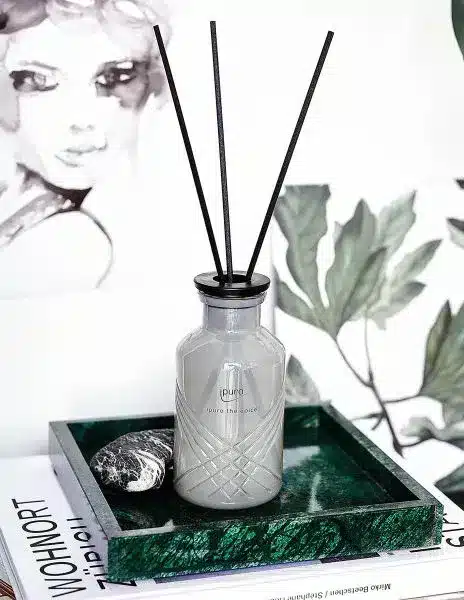 ipuro Exclusive thé épicé reed diffuser 240ml in a grey bottle on a tray with green branches